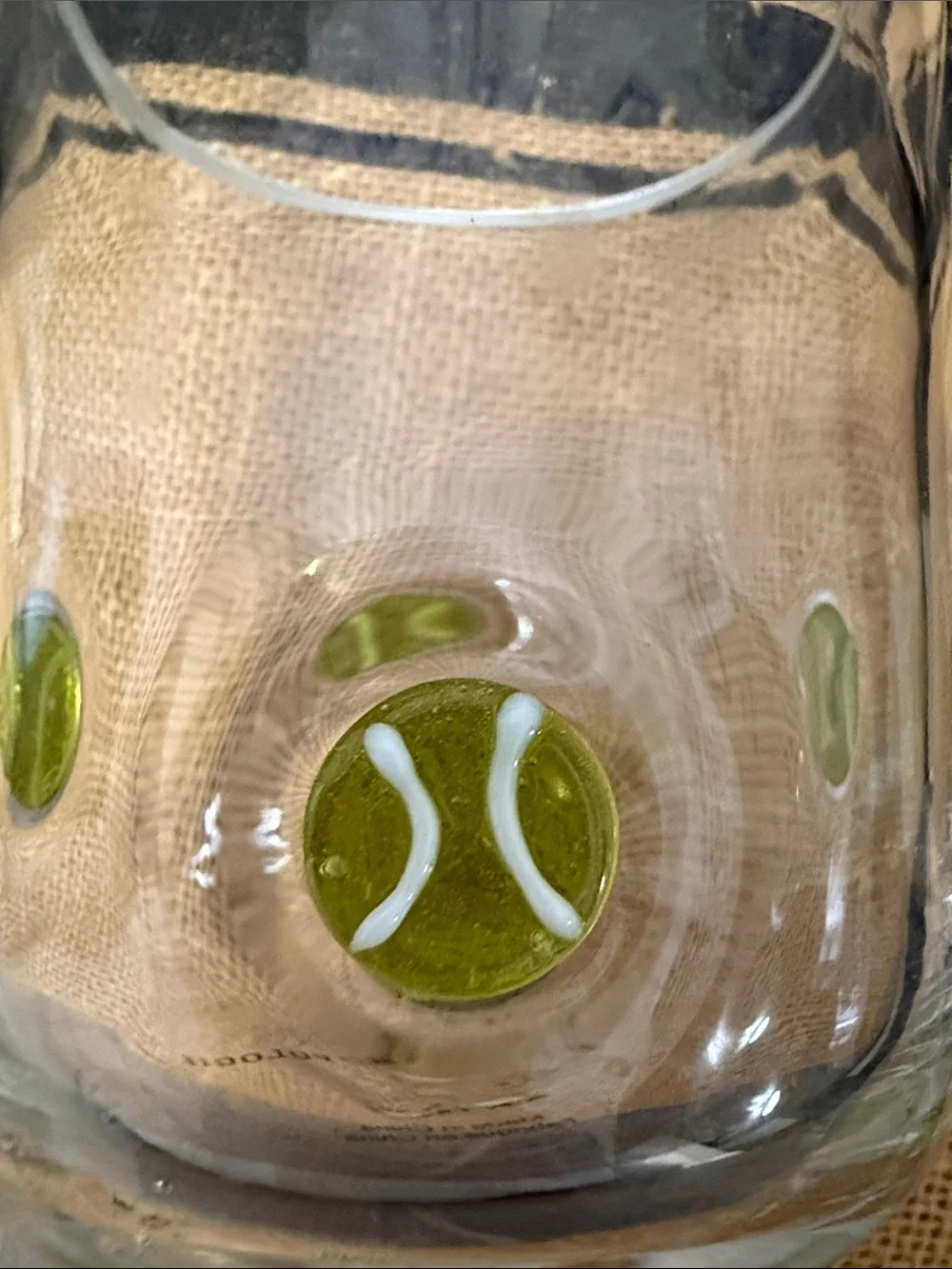 Anthropologie Clear drinking glass with yellow/green tennis ball accents.